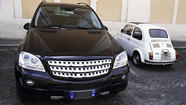 Symbolbild: Sehr grosser schwarzer SUV parkt neben einem sehr kleinen weissen Fiat 500.  | Bild: picture alliance / Zoonar | Bernhard Kuh