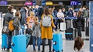Passagiere vor ihrem Flug nach Mallorca stehen vor einem Check-in-Schalter am Flughafen | Bild: picture-alliance/dpa