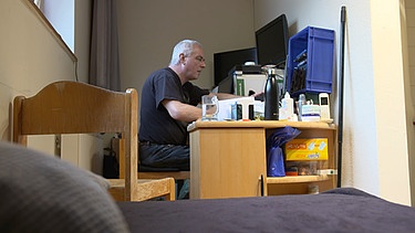 Mann sitzt im Männerwohnheim am Tisch | Bild: BR / Kontrovers | Thomas Kießling