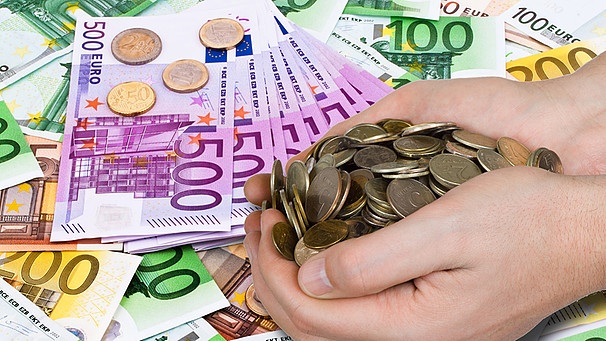 Haufenweise Bargeld in Form von Euroscheinen und zwei Händen, die Münzen halten | Bild: colourbox.com; Montage: BR