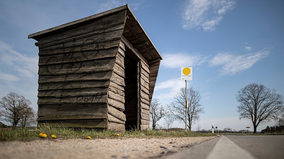 Eine Holzhütte steht als Bushaltehäuschen an einer Bushaltestelle an einer Landstrasse. | Bild: picture alliance / photothek | Florian Gaertner