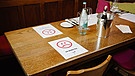 Hinweisschilder zu den Abstandsregeln auf einem Tisch in einer Gaststätte | Bild: picture alliance/Uwe Anspach/dpa