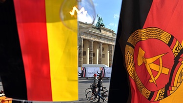 Die Flagen der BRD und der DDR flattern vor dem Brandenburger Tor | Bild: BR