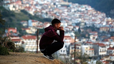 23.02.2021, Griechenland, Samos: Ein Migrant sitzt auf einem Hügel außerhalb des überfüllten Flüchtlingslagers am Hafen von Vathy auf der ostägäischen Insel Samos. Foto: Thanassis Stavrakis/AP/dpa +++ dpa-Bildfunk +++ | Bild: dpa-Bildfunk/Thanassis Stavrakis