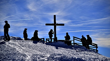 Symbolbild: Ausflügler stehen am Gipfelkreuz und bewundern die Aussicht | Bild: picture-alliance/dpa