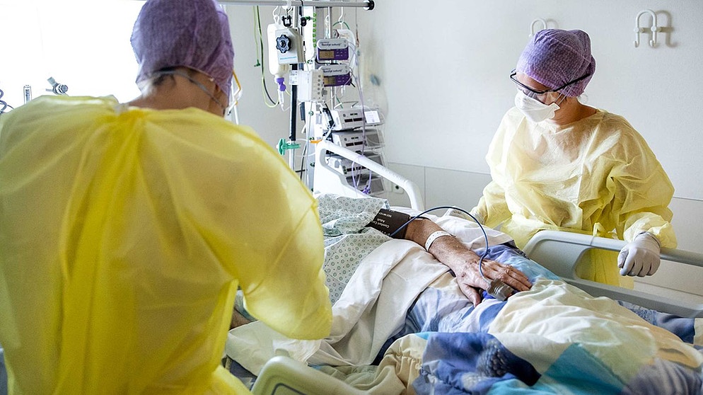 Pflegekräfte an einem Intensivbett mit Beatmungsgerät | Bild: picture-alliance/dpa