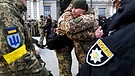 Ukrainische Soldaten verabschieden sich Anfang März von ihren Familien, um in den Krieg gegen Russland zu ziehen.  | Bild: picture alliance / ZUMAPRESS.com | Carol Guzy
