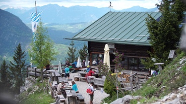 
Mit Abstand sitzende Gäste auf der Terrasse einer Berghütte | Bild: BR