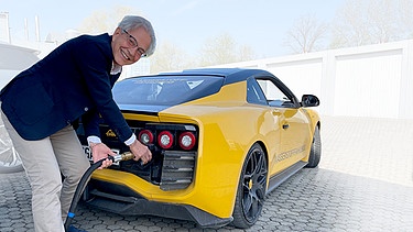 Roland Gumpert tankt sein Elektroauto, das mit einer Methanol-Brennstoffzelle ausgerüstet ist. | Bild: BR