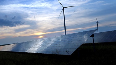 Windrad hinter einer Freiflächen-Photovoltaik-Anlage im Sonnenuntergane | Bild: picture-alliance/dpa | Karl-Josef Hildenbrand
