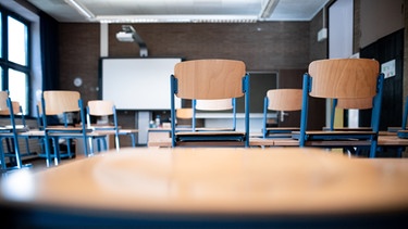 Stühle stehen auf Tischen in einem Klassenraum.  | Bild: picture alliance/dpa | Fabian Strauch