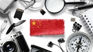 Chinesische Flagge umgeben von chinesischen Exportartikeln wie Chip, Fotokamera etc.  | Bild: picture alliance / Zoonar | Aleksey Butenkov