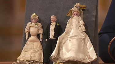 Nahezu in ihrem Originalzustand sind diese drei Puppenstubenpuppen aus thüringischer Herstellung erhalten: eine Brautjungfer, ein Bräutigam - und die Braut ganz in Weiß. Weshalb lässt sich die kleine Hochzeitsgeselschaft anhand ihres Kleides so gut datieren? Geschätzter Wert: 800 Euro | Bild: BR