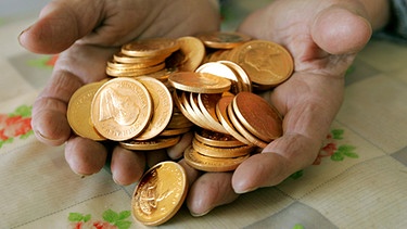 Hand mit Goldmünzen | Bild: picture-alliance/dpa