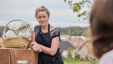 Landfrau Veronika Röll präsentiert den Gruß aus der Küche mit Gastgeschenken. | Bild: BR/megaherz gmbh/Philipp Thurmaier