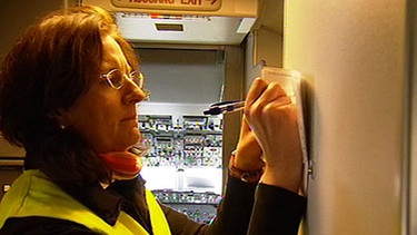 Frau hakt Liste ab, im Hintergrund Cockpit | Bild: BR