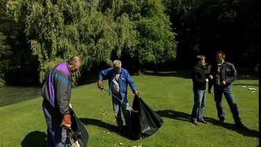 Männer sammeln Müll auf Wiese ein  | Bild: BR