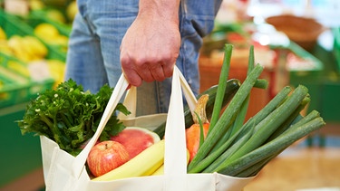Ein Mann mit einer Einkaufstasche, die mit Obst und Gemüse gefüllt ist. | Bild: stock.adobe.com/Robert Kneschke