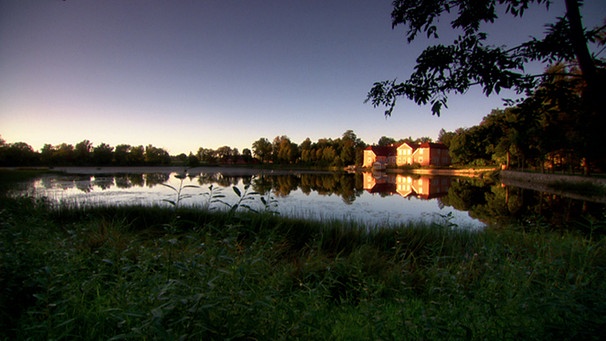 Ein Herrenhaus an einem See im Sonnenlicht | Bild: BR