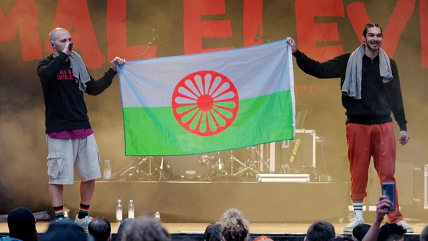Mal Élevé zeigt auf einem Konzert die Flagge der Roma. | Bild: BR