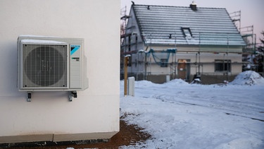 ARCHIV - 13.12.2022, Sachsen, Leipzig: Eine Luftwärmepumpe hängt bei Schnee und Eis an einer Hauswand in einem neu entstehenden Einfamilienhausgebiet. (zu dpa: «Diebstahl von Wärmepumpen in Sachsen und Sachsen-Anhalt nimmt zu») Foto: Jan Woitas/dpa +++ dpa-Bildfunk +++ | Bild: dpa-Bildfunk/Jan Woitas