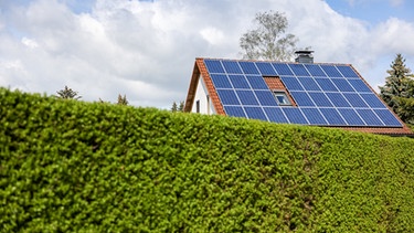 ARCHIV - 03.05.2021, Sachsen, Leipzig: Ein Einfamilienhaus mit Solarzellen auf dem Hausdach steht hinter einer grünen Hecke.     (zu dpa «Hohe Energiepreise sorgen für wachsendes Interesse an Solaranlagen») Foto: Jan Woitas/dpa-Zentralbild/dpa +++ dpa-Bildfunk +++ | Bild: dpa-Bildfunk/Jan Woitas