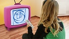 Montage: Ein Mädchen sitzt vor einem bunten Fernseher | Bild: colourbox.com