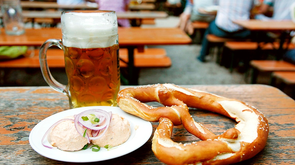 Eine Maß Bier, ein Teller Obazda und eine Riesenbrezel im Biergarten | Bild: picture alliance / Lajos-Eric Balogh | Lajos-Eric Balogh
