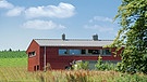 Ein Holzhaus mit einem Industrie-Blechdach wie eine Lagerhalle. Durch das "Sandwich"-Dach sparte die Bauherrin Kosten. | Bild: BR / Sabine Reeh
