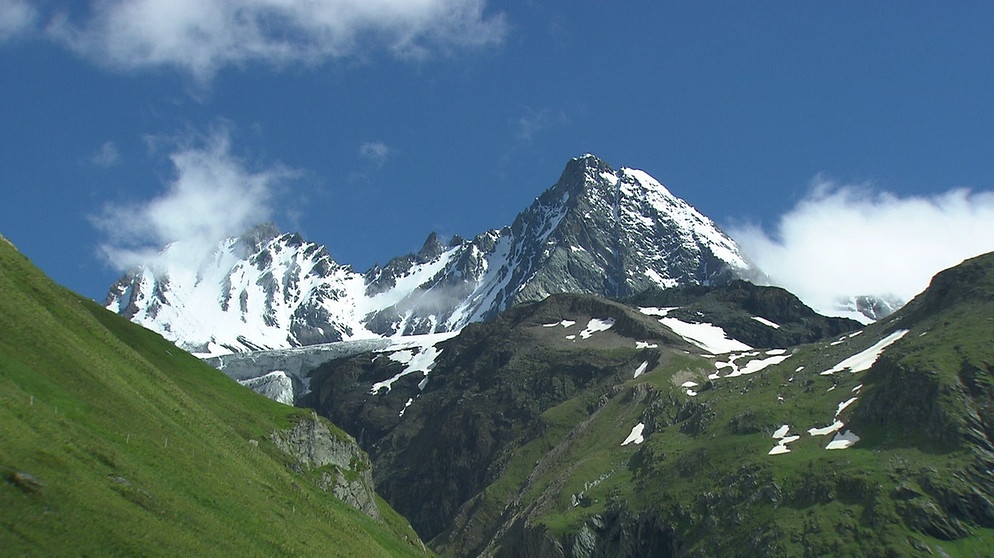Unter unserem Himmel - Klimawandel in den Alpen: Schneebedeckte Berge im Hintergrund, grüne Felsen im Vordergrund | Bild: BR