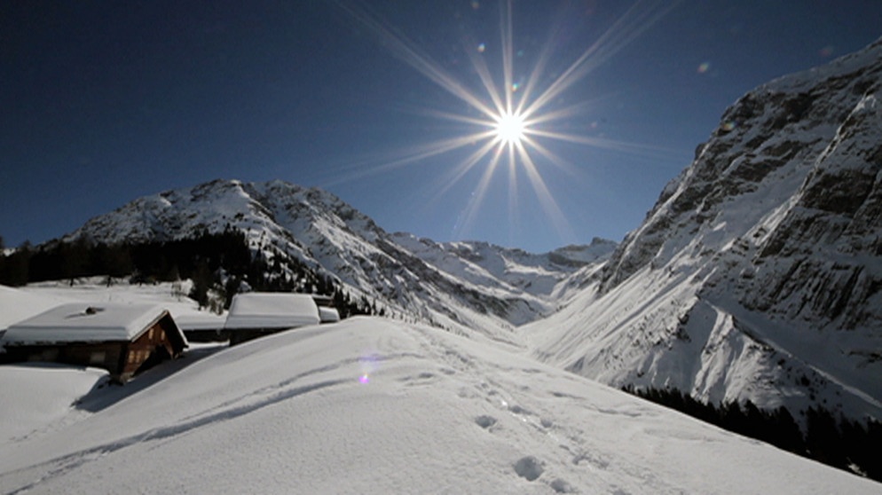 Unter unserem Himmel - Winter im Lechtal: Schneebedeckte Berglandschaft mit kleinen Holzhütten; die strahlende Sonne scheint am blauen Himmel | Bild: BR