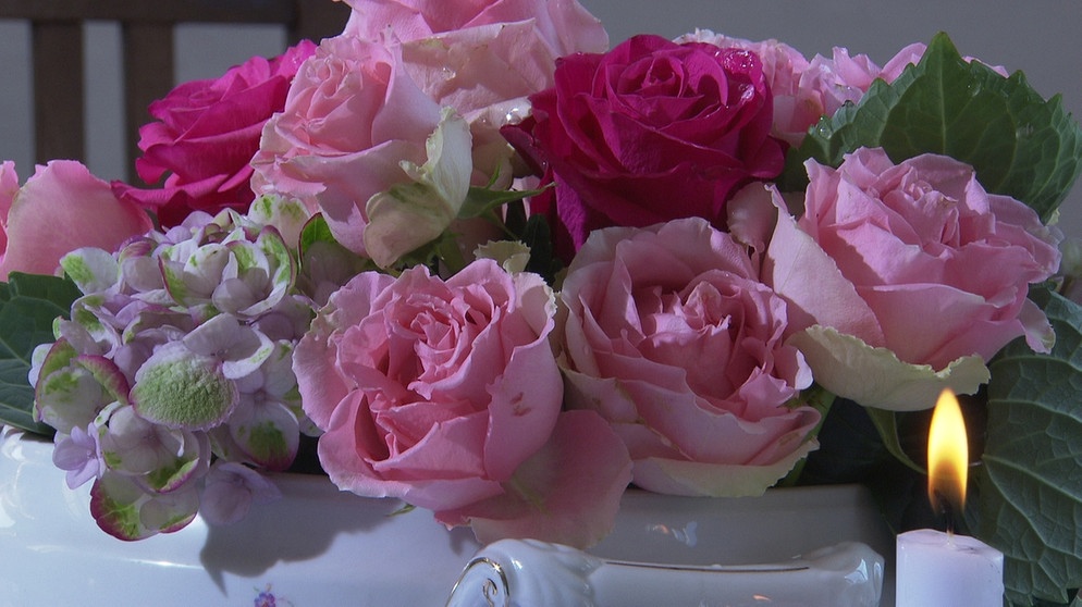Unter unserem Himmel - Zeit für Rosen: Ein Strauß rosa Rosen in der Vase, im Vordergrund links brennt eine Kerze | Bild: BR