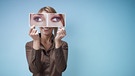 Eine Frau hält ein Bild mit schielenden Augen vors Gesicht | Bild: Colourbox