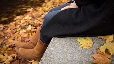 Frau sitzt auf kaltem Stein | Bild: picture-alliance/dpa/Christin Klose