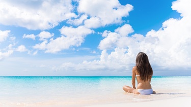 Eine Frau sitzt am Strand.  | Bild: Colourbox