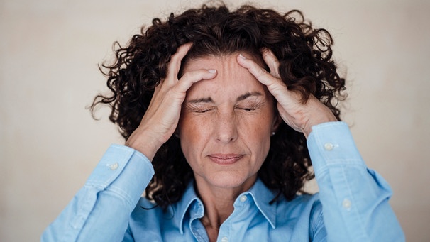 Frau mit Kopfschmerzen hält sich den Kopf und verzieht das Gesicht | Bild: picture-alliance/dpa/Westend61/Robijn Page