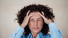 Frau mit Kopfschmerzen hält sich den Kopf und verzieht das Gesicht | Bild: picture-alliance/dpa/Westend61/Robijn Page