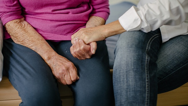 Eine Pflegerin hält die Hände einer Seniorin. | Bild: BR/Johanna Schlüter