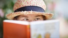 Kind liest mit Sonnenhut ein Buch. | Bild: picture alliance 