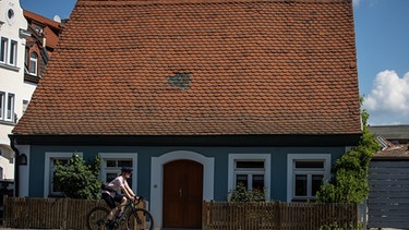 Katharina Kestler fährt an einem Haus in der Gärtnerstadt vorbei. | Bild: BR/Jens Scheibe
