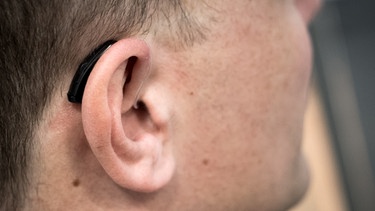 Ein Mann trägt ein Hörgerät. | Bild: picture-alliance/dpa/Alexander Heinl