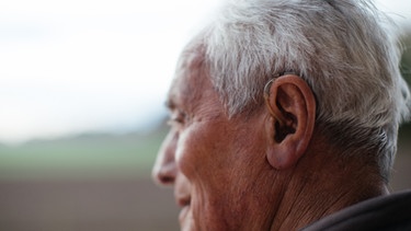 Ein älterer Herr mit kaum sichtbarem Hörgerät im Ohr | Bild: BR / Julia Müller