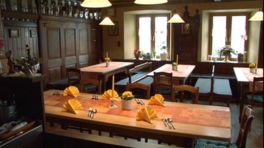 Gasthaus Straub innen, Tische aus hellem Holz, Orange-gelbe Tischdeko. | Bild: BR