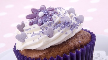 Muffin mit einem Sahnetopping und lila Blumendekor | Bild: colourbox.com