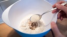 In einer Schüssel wird Mehl mit Hefe und Zucker vermischt. | Bild: picture-alliance/dpa