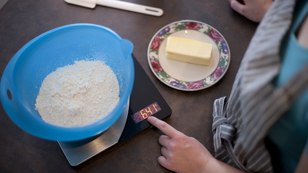 Beim Backen: eine Küchenwaage, eine Schale mit Mehl und ein Teller mit Butter | Bild: picture-alliance/dpa
