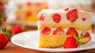 ein Stück Erdbeer-Biskuit-Kuchen auf einem weißen Teller mit zwei Erdbeeren | Bild: 	mauritius images / Natalia Peredniankina / Alamy / Alamy Stock Photos