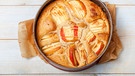 Ein veganer Apfelkuchen - aus Rührteig mit halbierten Äpfeln - in einer Springform auf einem hellen Holztisch von oben fotografiert | Bild: mauritius images / Pitopia / Bernd Jürgens