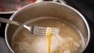 Spaghetti Nudeln kochen in einem Topf mit Wasser auf einem Herd in der Küche. Nudel auf einer Gabel um die Nudel auf All dente zu testen | Bild: picture alliance / CHROMORANGE | Michael Bihlmayer