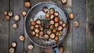 Eine gusseiserne Pfanne von oben fotografiert mit ganzen Champignons, Knoblauch und Petersilie; die Pfanne steht auf einem dunkelbraunen Holztisch. | Bild: mauritius images / Westend61 / Larissa Veronesi